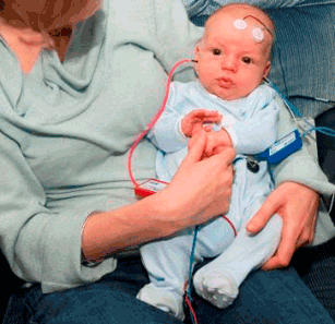Adult holding an infant with various monitoring devices