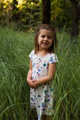 Young girl with standing in tall grass smiling